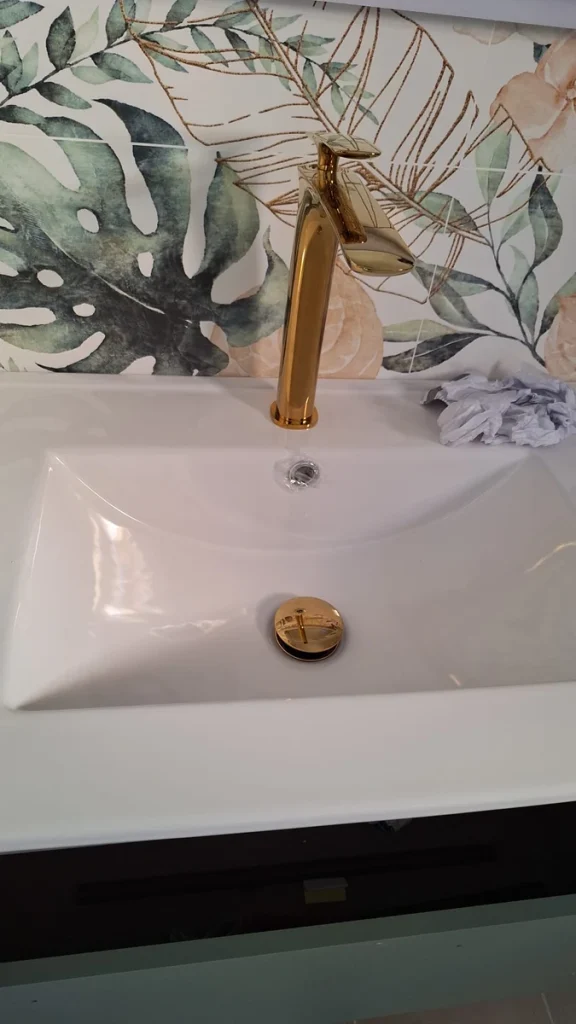 Grifería dorada alta instalada sobre lavabo blanco en un baño reformado en Murcia