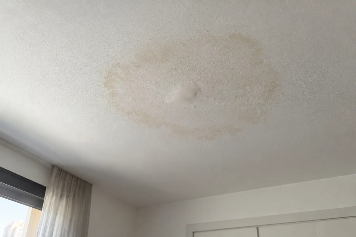 Mancha de humedad circular en el techo de una habitación, señal habitual de una fuga de agua en el piso superior
